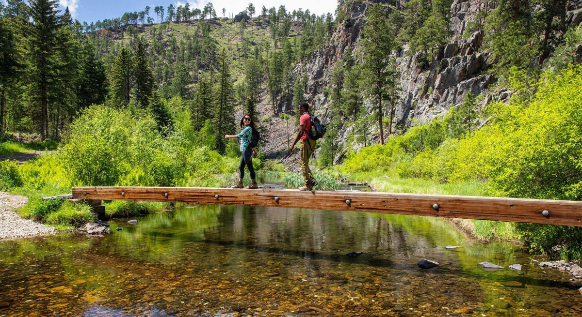 Two hikers cross a bridge on the spring creek portion of the centennial trail in south dakota