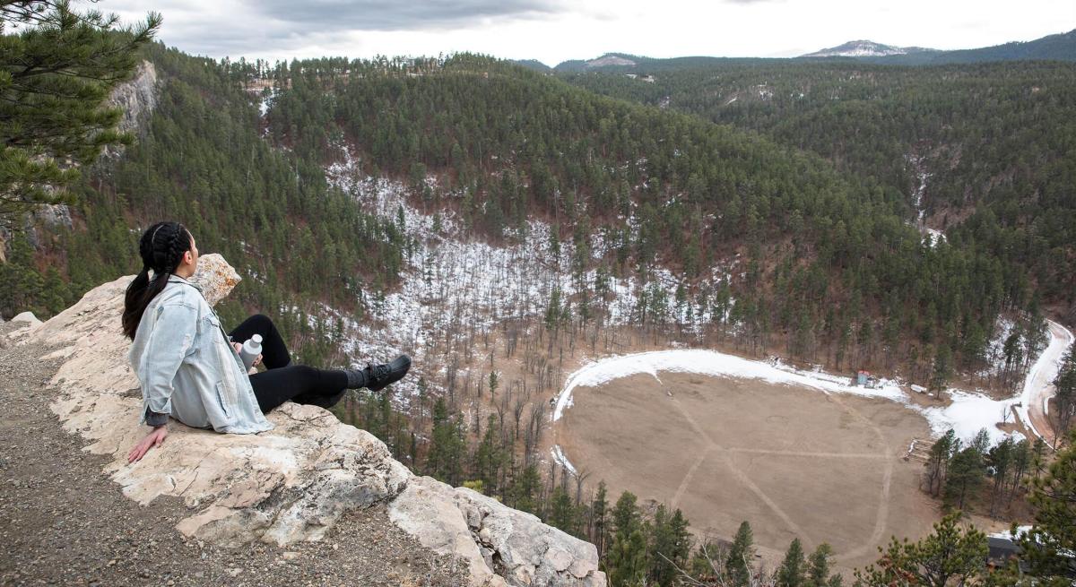 winter hiker sitting on the top of the stratobowl rim trail in the black hills of south dakota