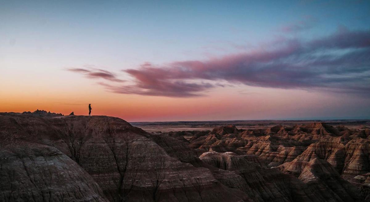 Sunrise signing on the Badlands with a hiker taking in the view