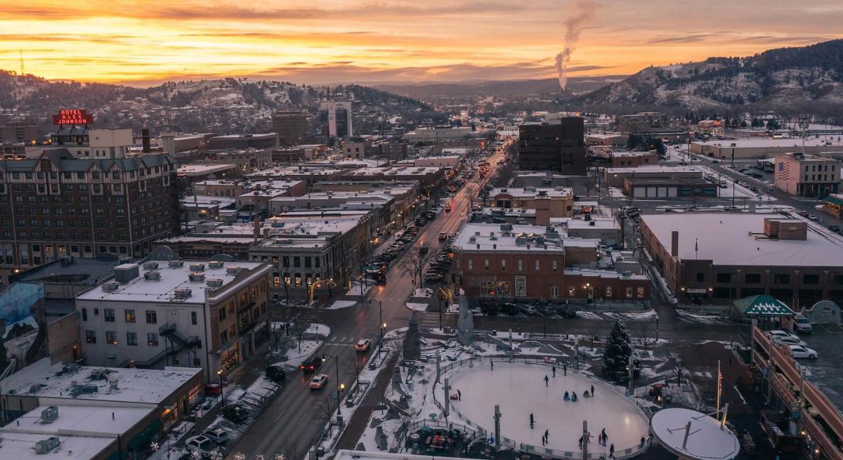 Drone shot of the sun setting over a snow covered downtown rapid city, sd