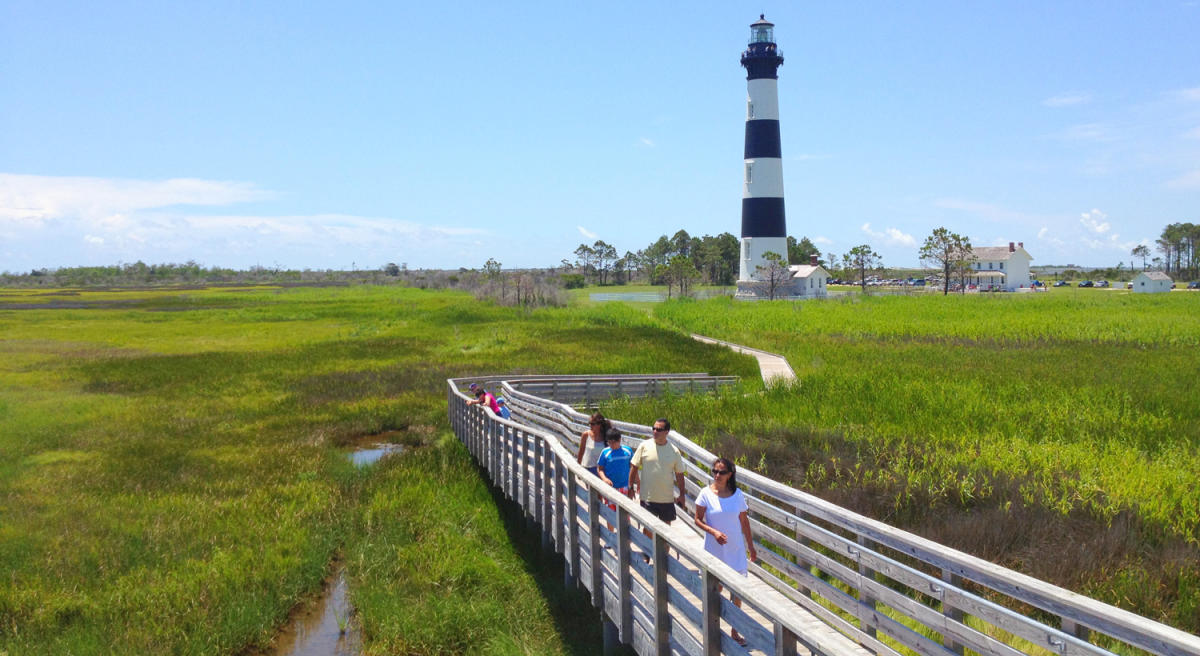 Visitors walking the boardwalk and looking at the lush marsh at Bodie Island Lighthouse.