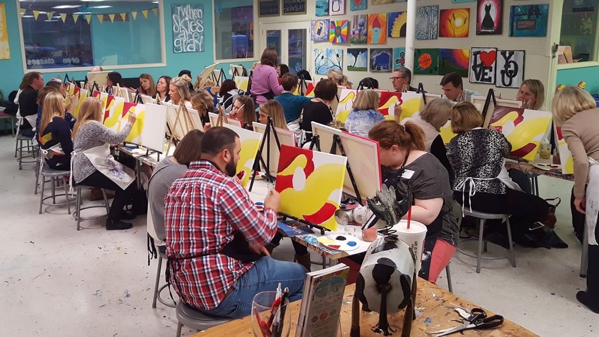 Men and women paint on canvas during a session at Paint the Towne in Wichita, KS