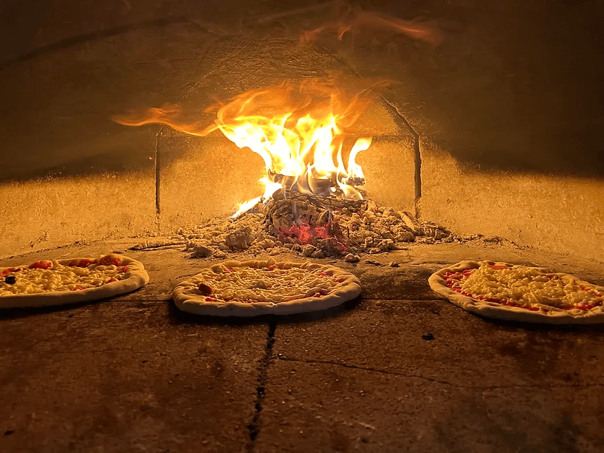 Fresh pizzas baking in an open flame brick oven, a fine dining romantic date night restaurant spot near Cheyenne.