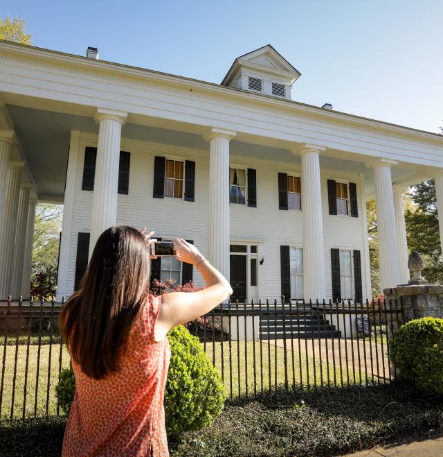 Woman taking picture of historic home in Milledgeville