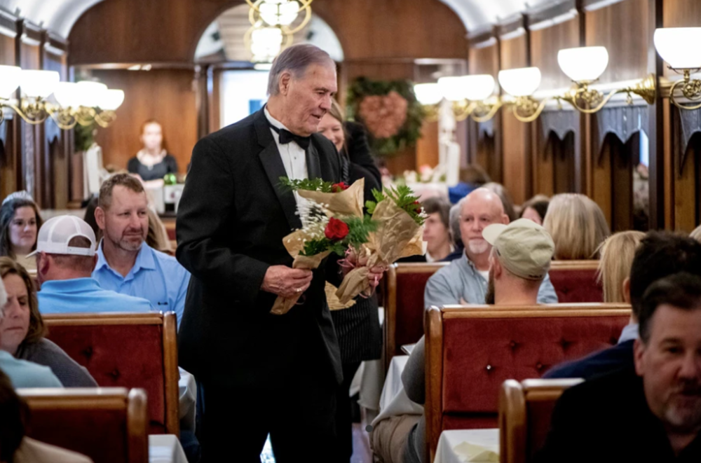 Man in suit on train holding bouquet