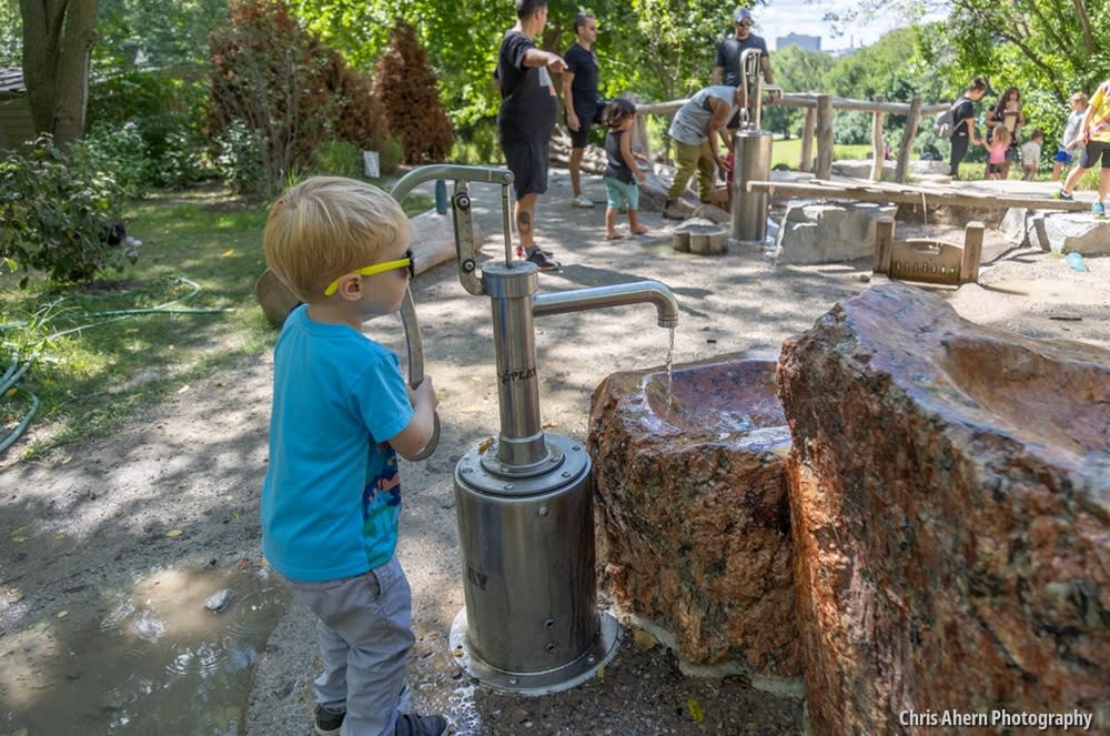 Child uses water play pump at Leslie Science and Nature Center