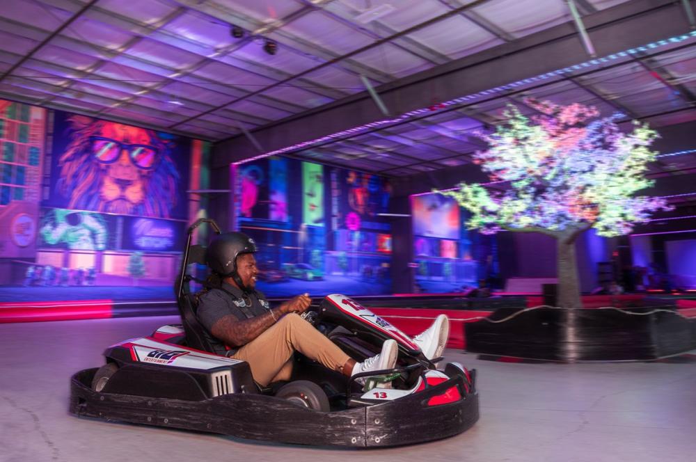 person riding a go-kart in action riding around an indoor track.