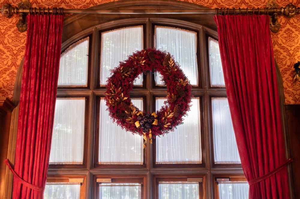 A large crimson wreath adorns a window inside the Library during Christmas at Biltmore