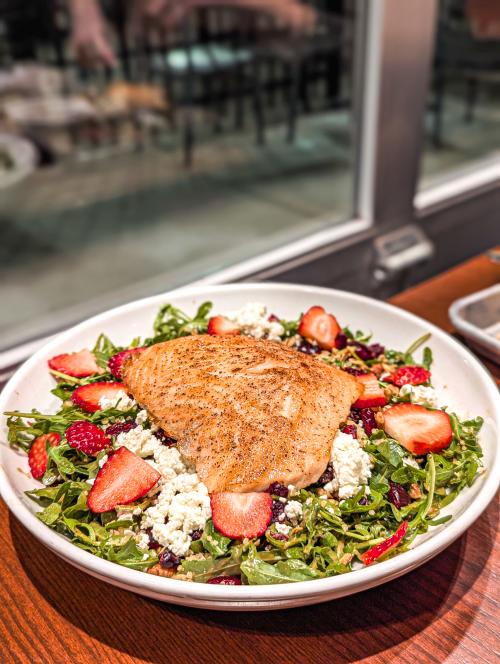 Grilled salmon served over an arugula salad with sliced strawberries, dried cranberries and crumbled cheese at Goodland Pour House.