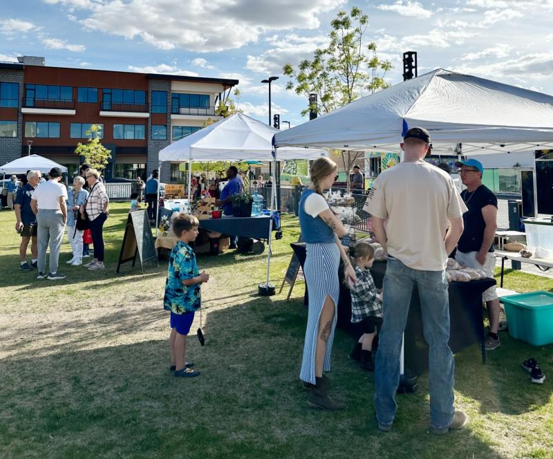 An image of some people shopping vendors at the Winrock Park Market.