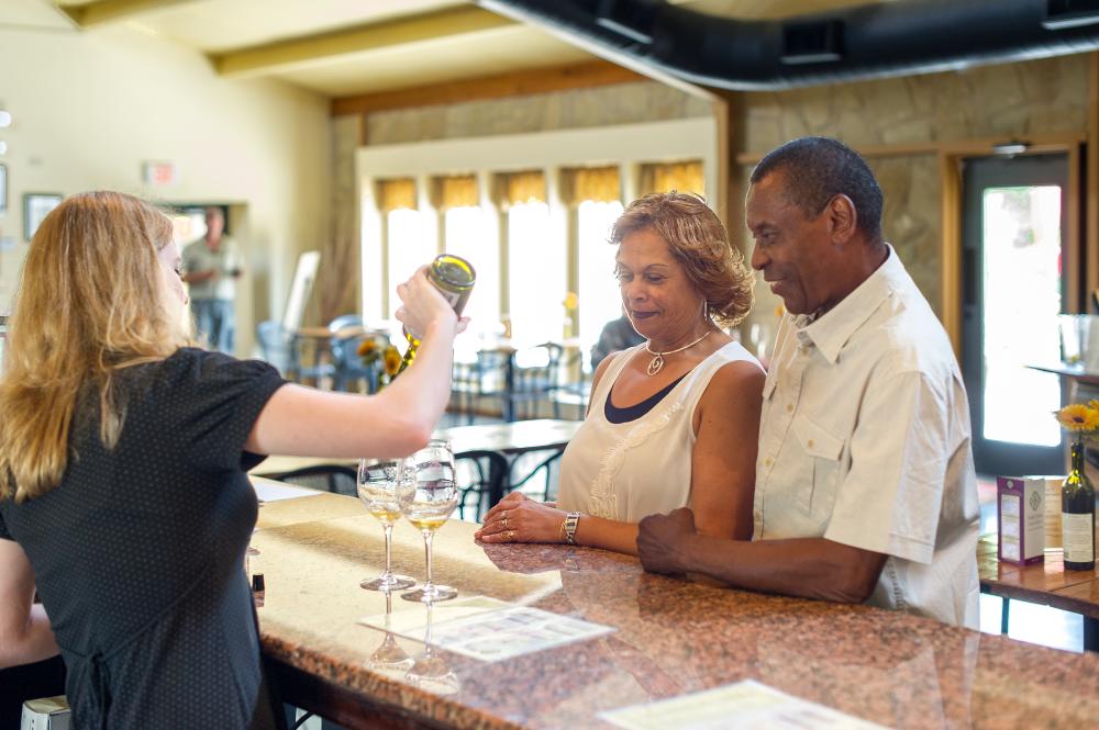 couple watching as woman pours samples of wine at Inwood Estates winery in Fredericksburg Texas