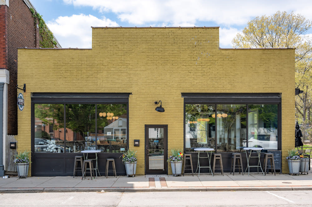 Grassroots & Vine in Ft. Thomas is a one-story orange brick building with two large windows facing the sidewalk and a handful of patio tables
