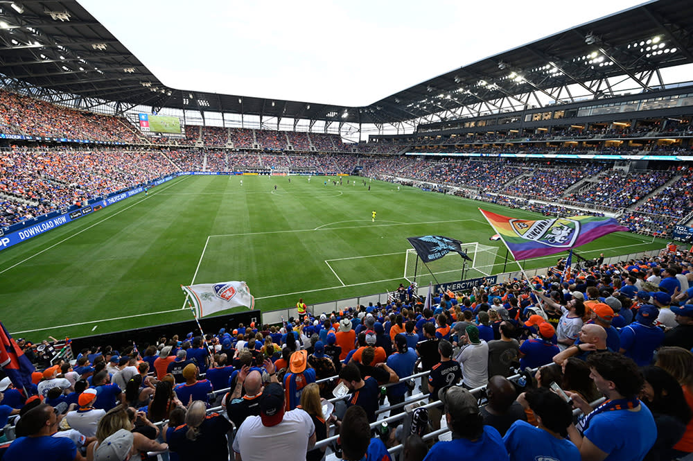 Fans wearing orange and blue sit inside the FC Cincinnati soccer stadium