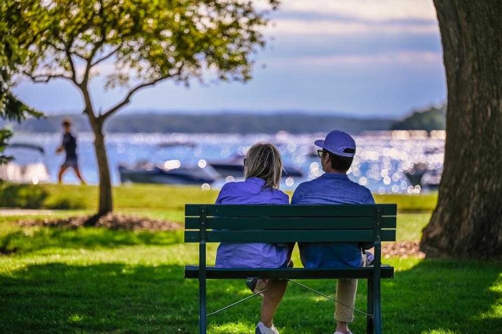 Couple sitting on a bench looking at the lake along the shorepath.
