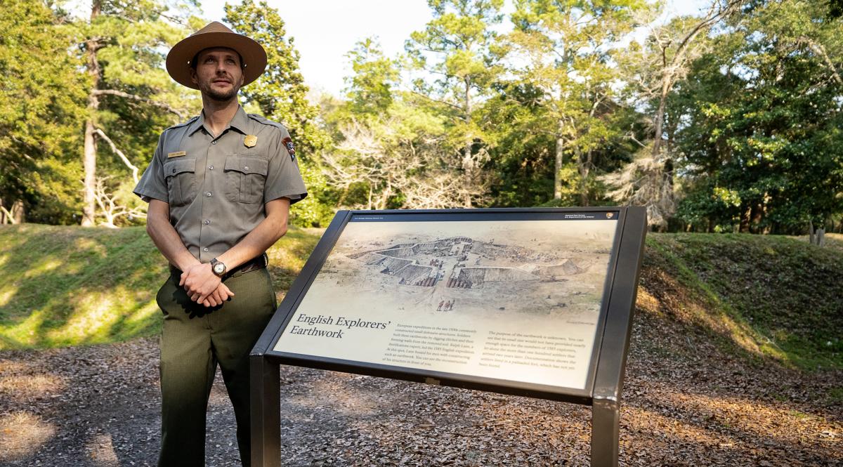 A park ranger stands in front of a sign at the site of Fort Raleigh in Manteo, NC.