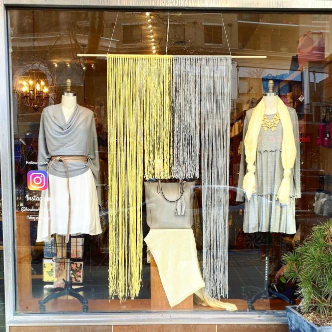 A window display of gray and yellow clothing at lou lou boutiques.