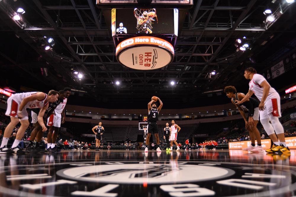 Austin Spurs basket ball player mid-shot for a free point while other basketball players line up along the lane.