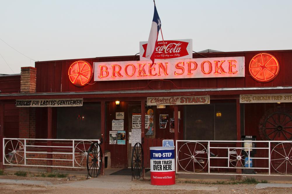 exterior of the Broken Spoke dance hall with texas flag and red neon sign