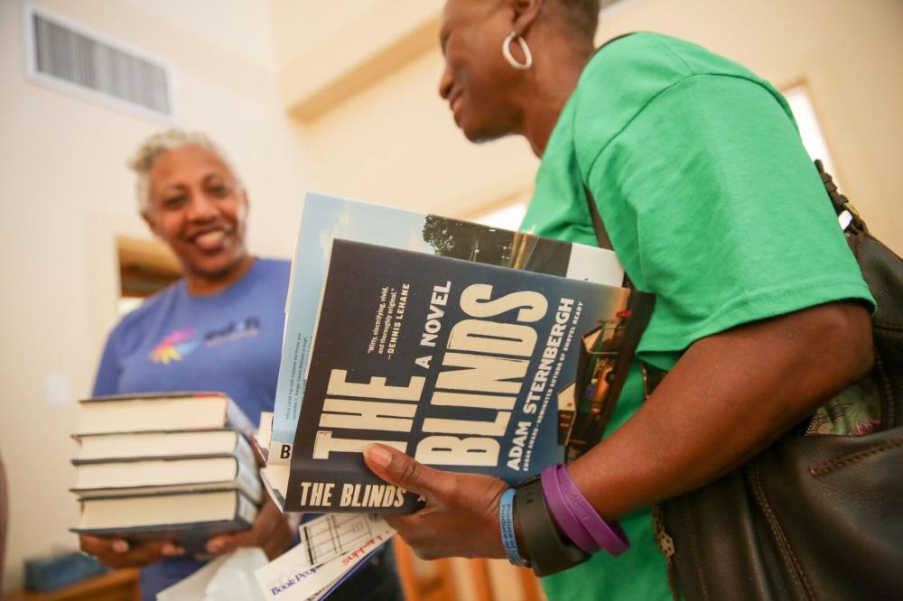 two women stand together one holds book titles The Blinds A NovelTexas Book Festival