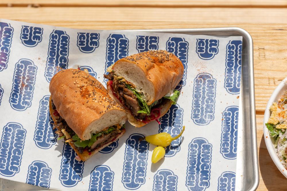 Image of sandwich sliced into two halves sitting on a tray on a wooden table.