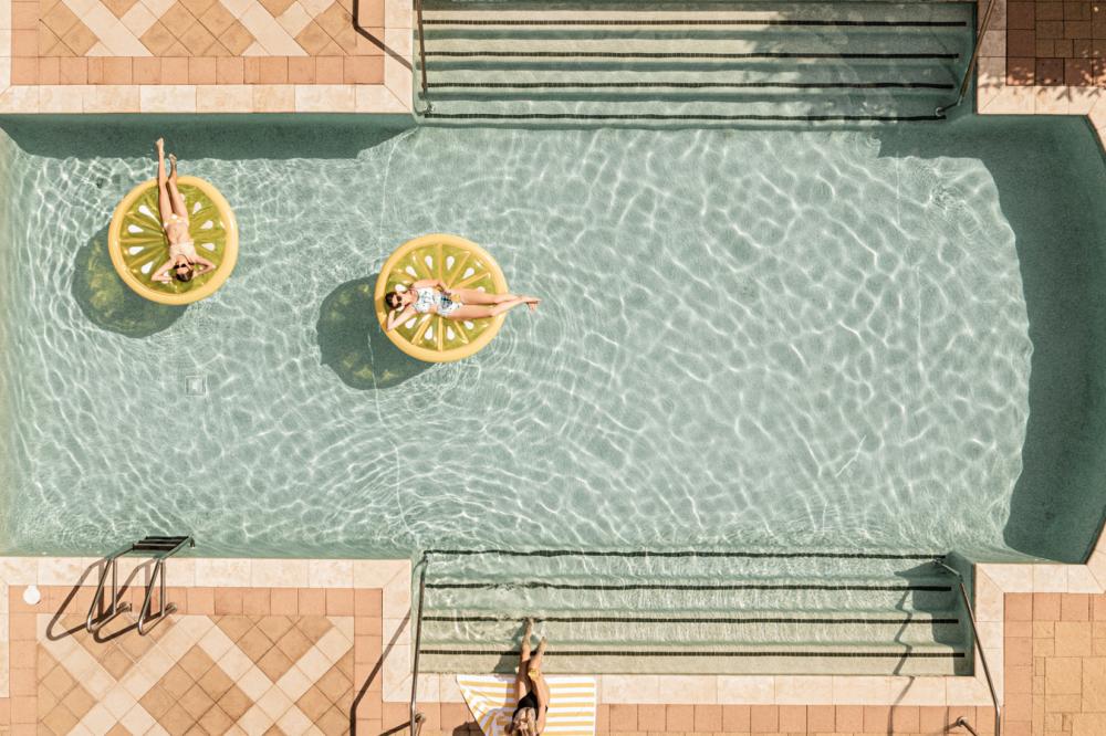 Women floating on lemon slice floaties in Hotel Granduca pool