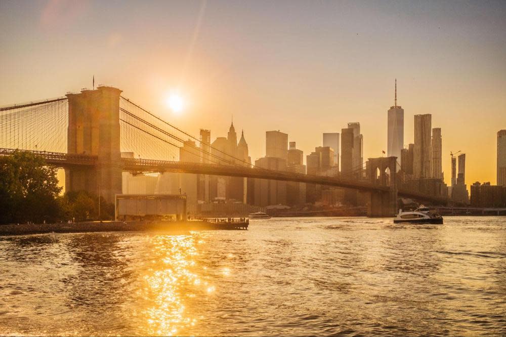 Sunset view of the Brooklyn Bridge and Lower Manhattan skyline from the East River.