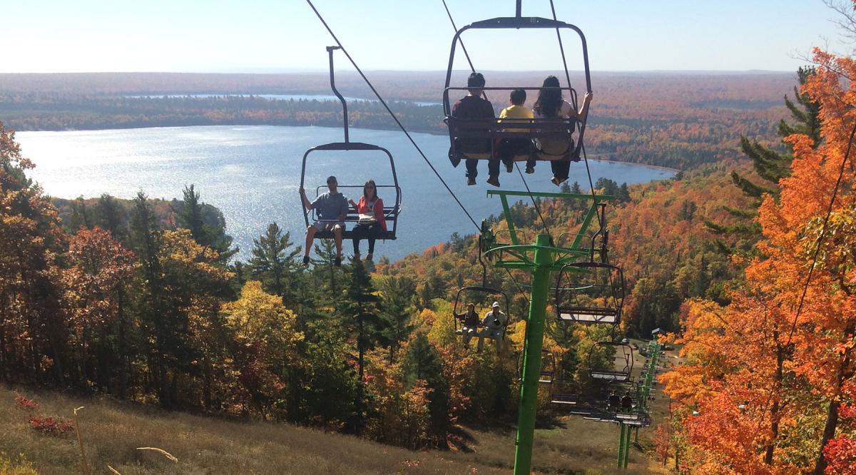 Visitors enjoy a ride on Mount Bohemia's chairlift with views of Lac La Belle