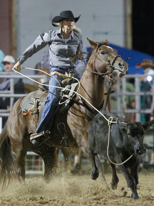 A cowboy rides a horse and ropes a bull.