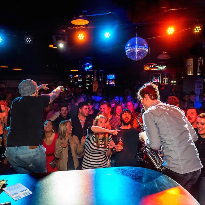 Crowd cheering to live stage performers at Howl at the Moon music bar