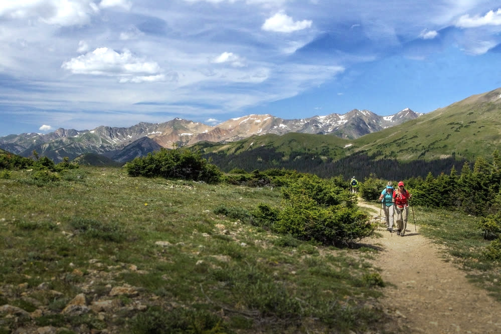 Woman with hiking sticks walking on a Rocky Mountain National Park trail