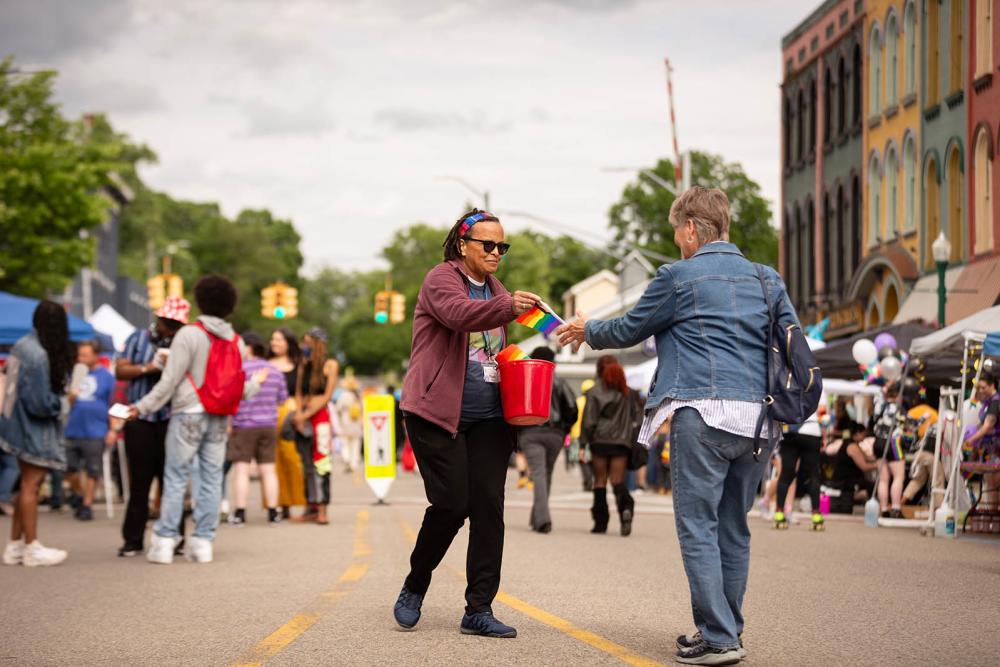 Woman handing out rainbow flags at Ypsi Pride