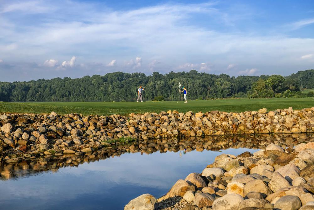 Man and woman on scenic tee with rocks and water surrounding, at Eagle Crest