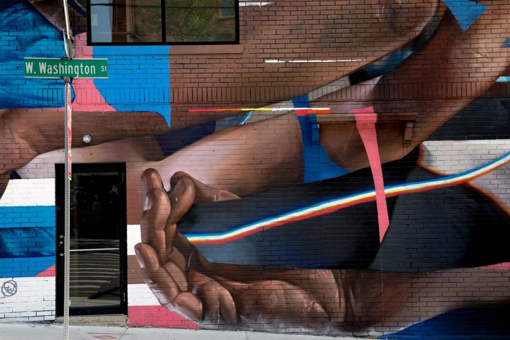 Mural Washington & First street artist taylor white painted on brick wall. abstract hands and rainbow line in the mural