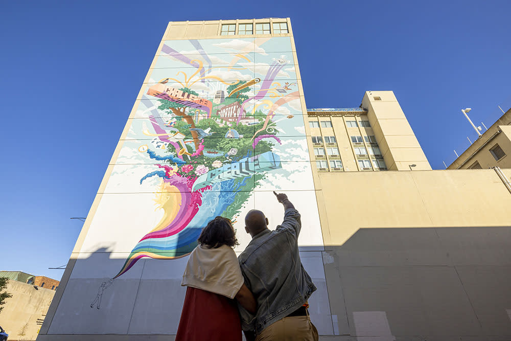 Couple pointing to Challenge Everything mural