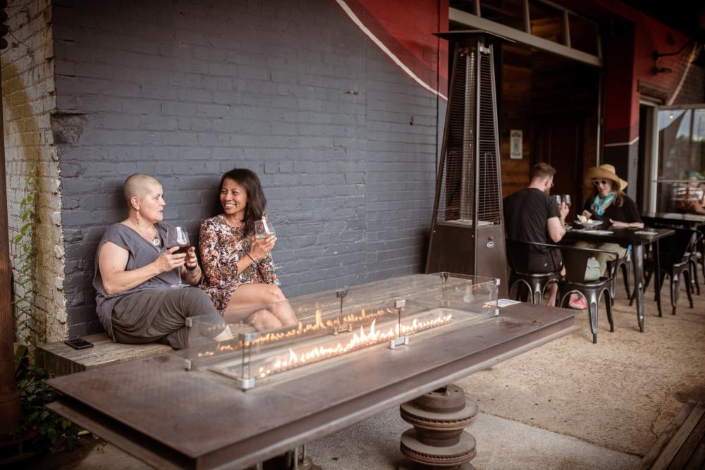 two people drinking wine near an outdoor fire place