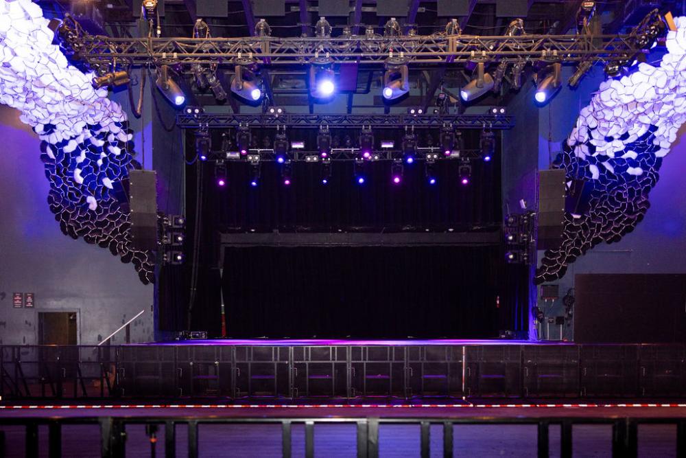 Empty stage at Emo's, with barricades in front and decorative murals on the side.
