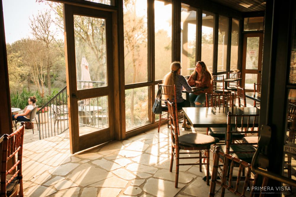 Two women having a wine tasting on screened in patio at Fall Creek Vineyards in Driftwood Texas