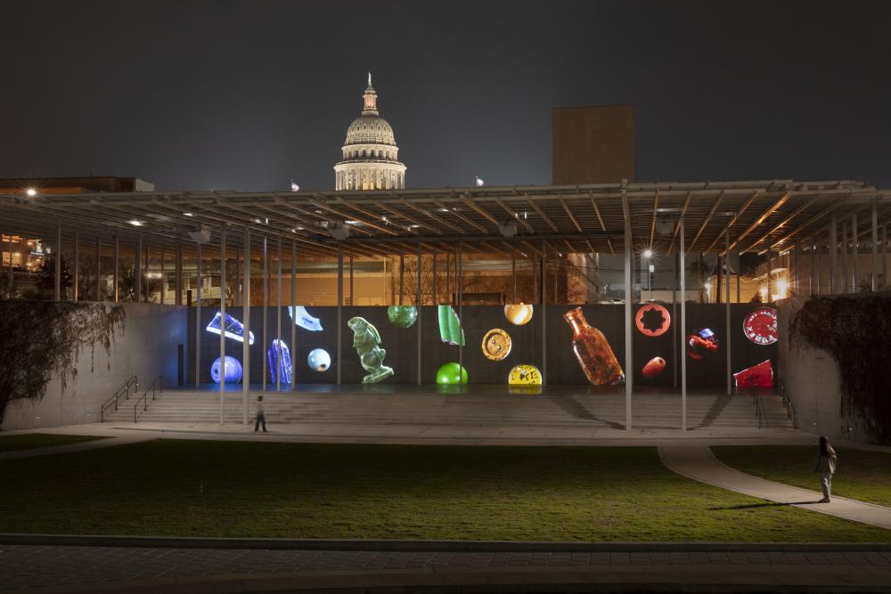 Person walking past digital mural with different rainbow-colored icons.