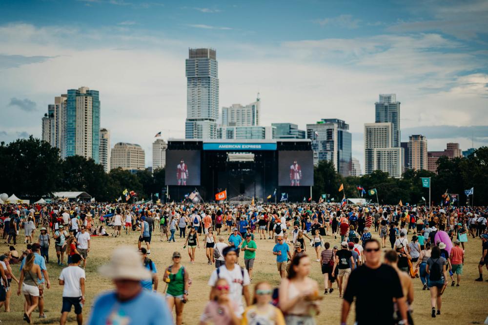 Wide view of ACL Fest crowd at Zilker Park, with large stage and downtown skyline in the background.