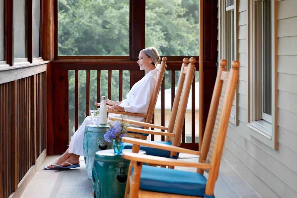 Woman in robe sitting in rocking chair on screened patio at Lake Austin Spa Resort