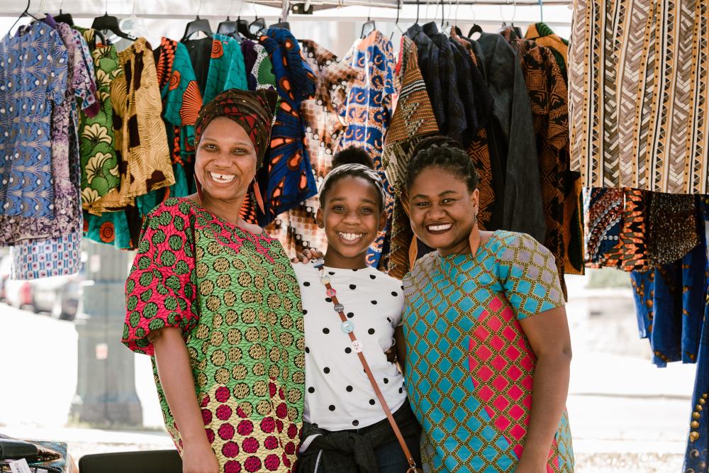 Three women in front of colorful garments at the outdoor Black Makers Market in Austin Texas