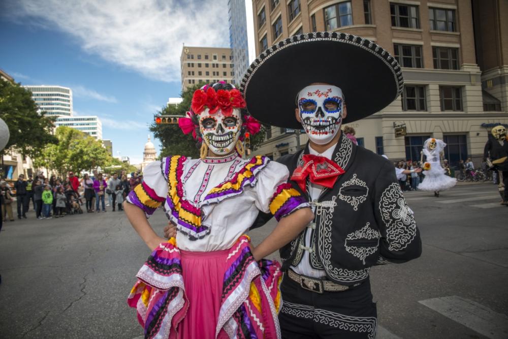 man and woman with dia de los muertos face paint and traditional clothing at Viva la Vida street parade in austin texas