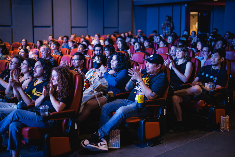 People sitting in theater seats clapping.