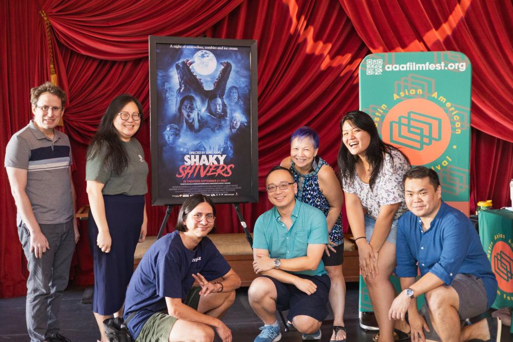 People standing in front of large movie posters at the Austin Asian American Film Festival.