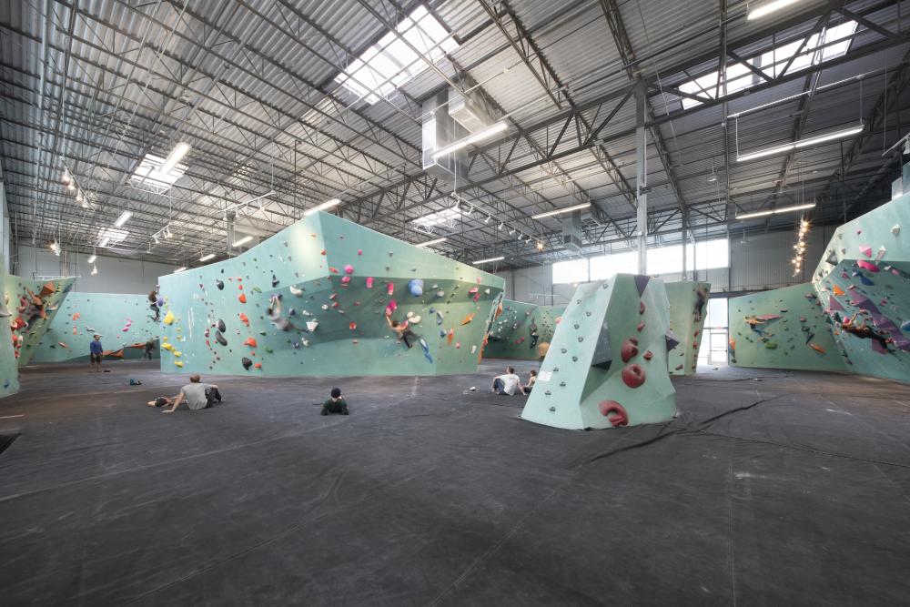 Multiple teal rock climbing walls with boulderers