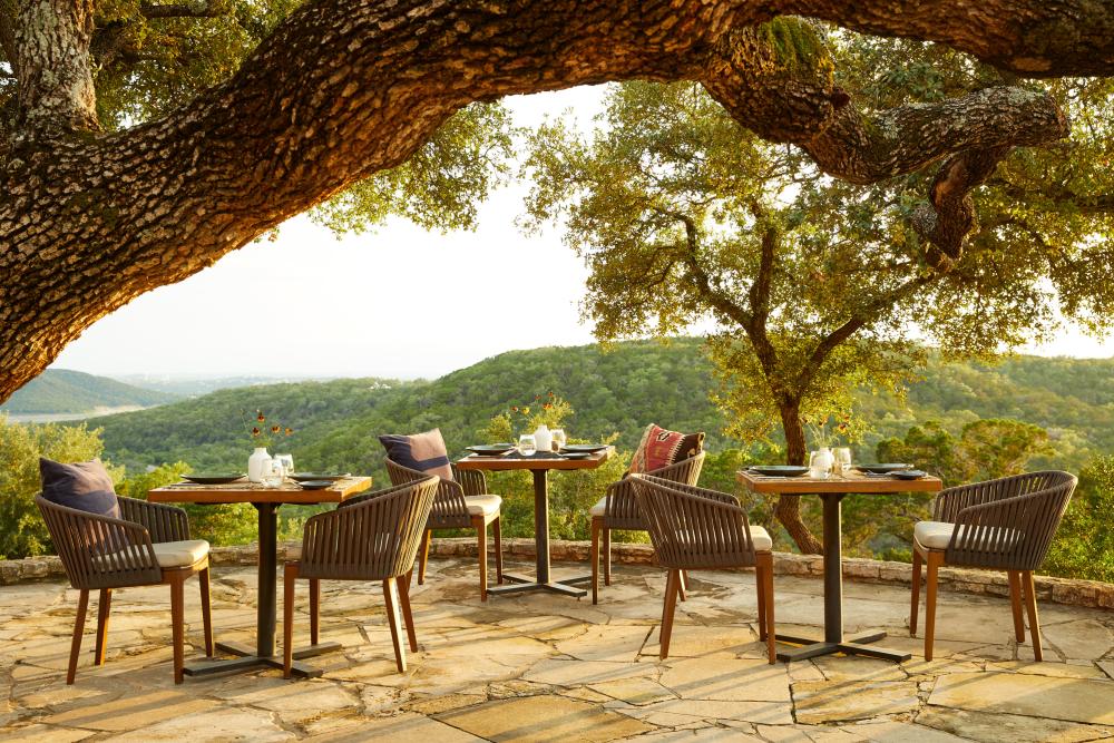 Image of the outdoor patio with tables overlooking the green rolling hills of the Texas Hill Country.