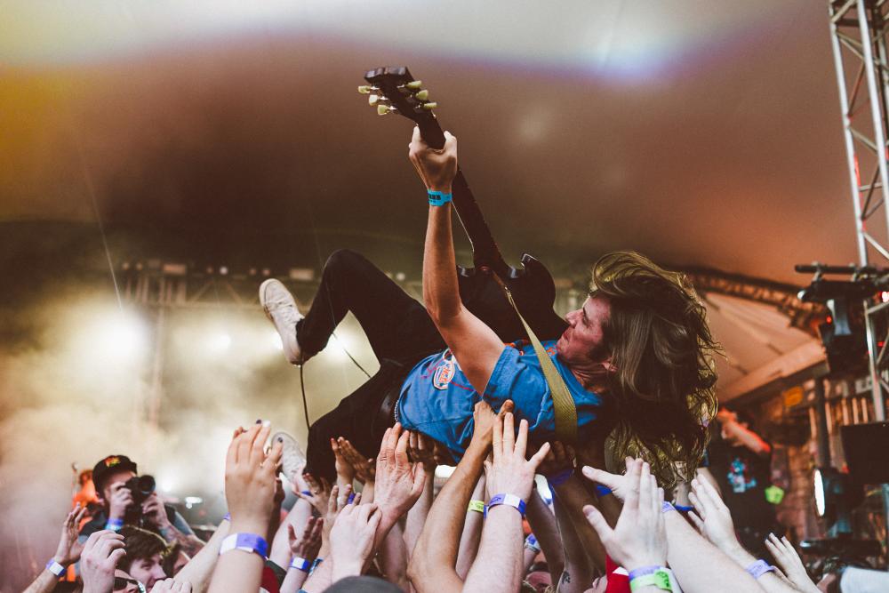 Guitar player crowd surfing in a sea of hands.