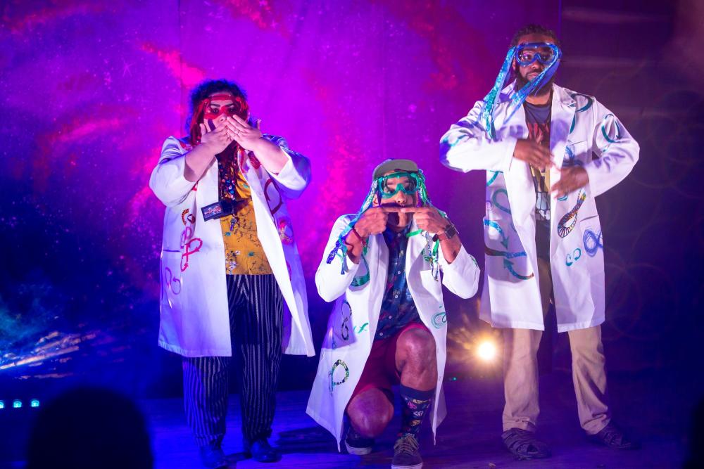 Photo of a performance of Annie Jump and the Library of Heaven at VORTEX theater. Three actors are pictured, all wearing lab coats and dressed as mad scientists