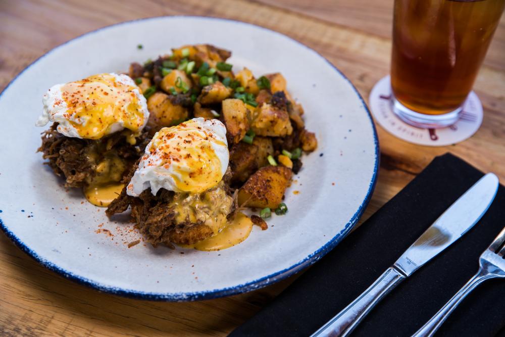 Loaded plate topped with fried breakfast potatoes, shredded barbacoa, soft poached eggs and bright hollandaise sauce.