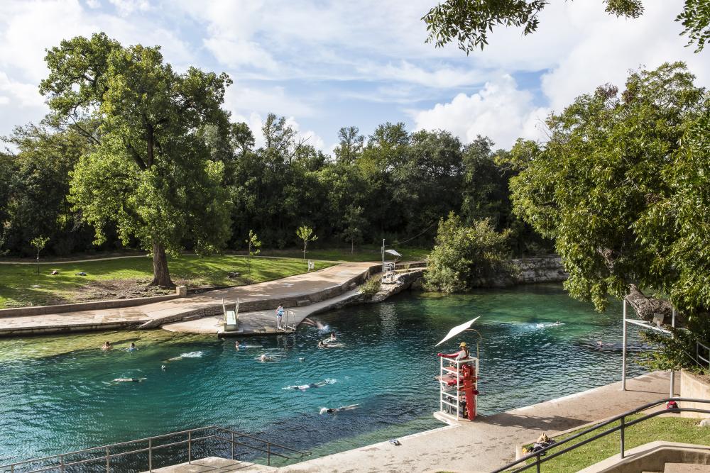 People swimming in Barton Springs Pool with lifeguard in stand